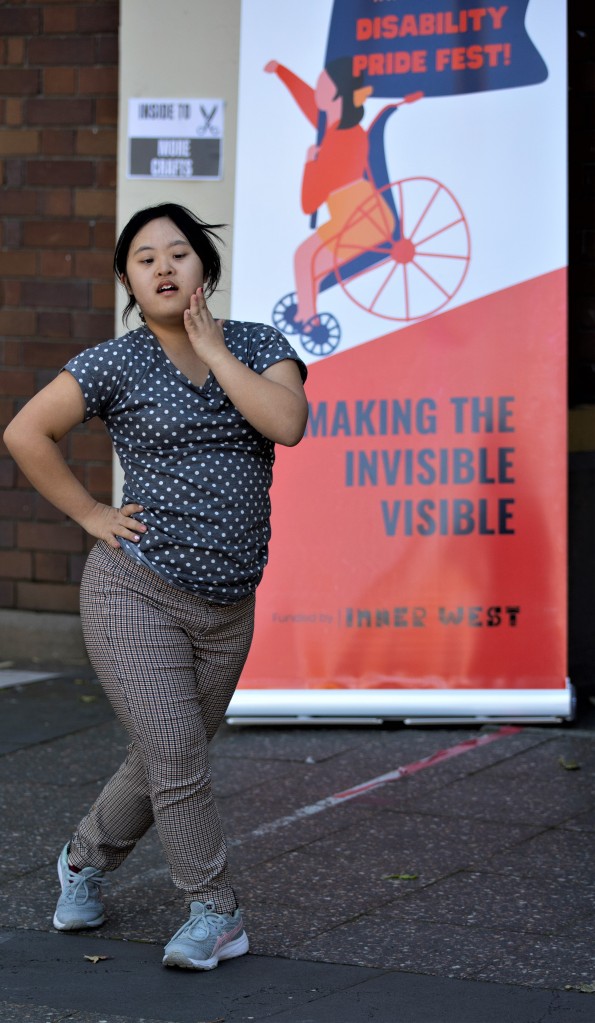 Woman dancing in front of Disability Pride Banner.